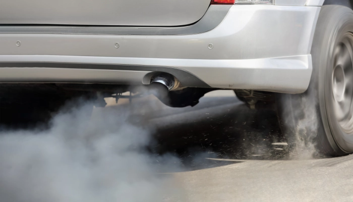 Escape de un carro liberando humo azul, señal de que el motor está quemando aceite