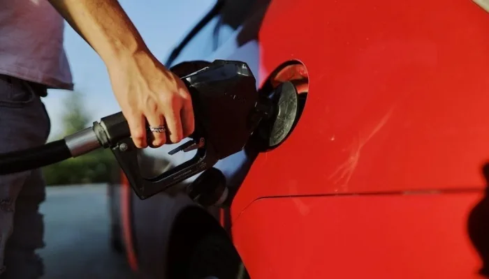 Persona echando gasolina a su carro en una estación de servicio