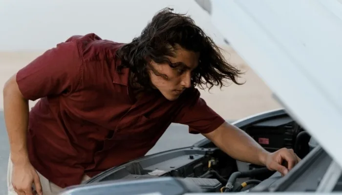 Persona revisando el motor de un carro usado antes de comprarlo