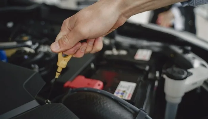 Mano revisando la varilla de aceite de un carro usado