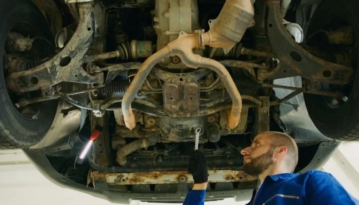 Mecánico revisando la parte baja del motor de un carro usado en busca de fugas de aceite