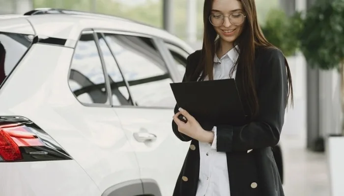 Compradora revisando los papeles de un carro usado antes de la compra