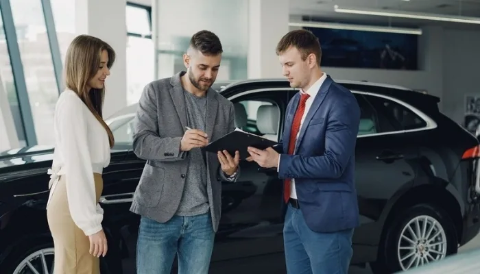 Comprador y vendedor revisando documentos de un carro usado
