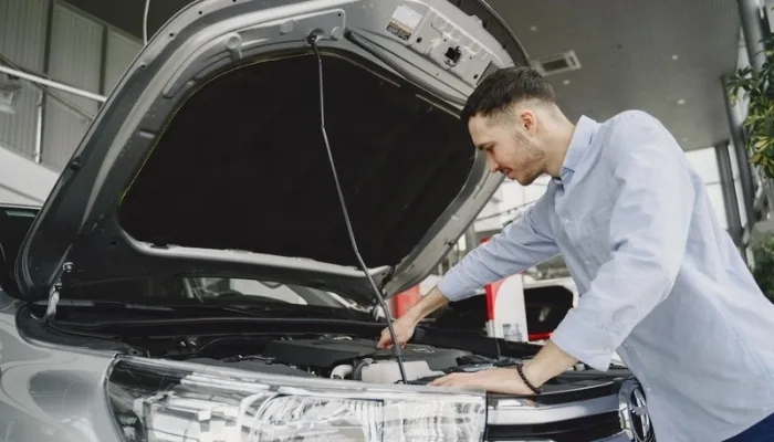 Comprador revisando un carro usado con el capó abierto en Venezuela