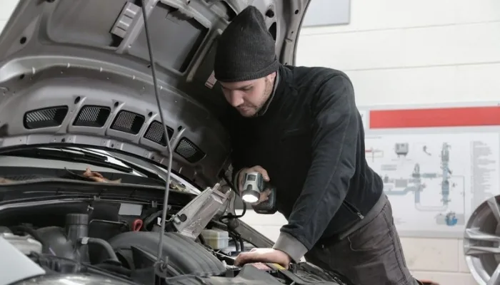 Mecánico revisando el motor de un carro usado con una linterna antes de la compra